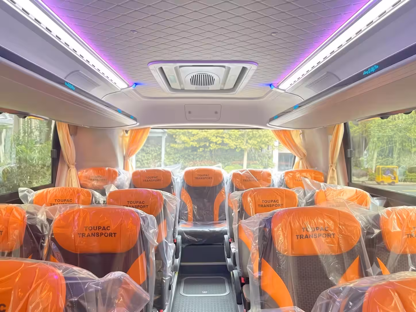 Cabine passagers d'un bus Toupac Transport avec sièges orange et éclairage intérieur
